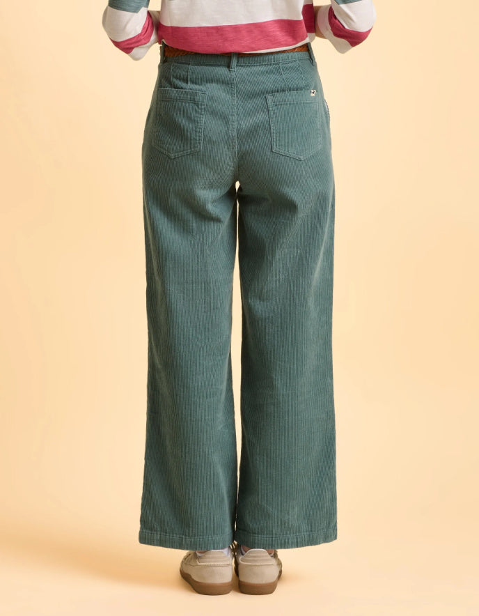 Person wearing teal wide-leg jeans on a beige background