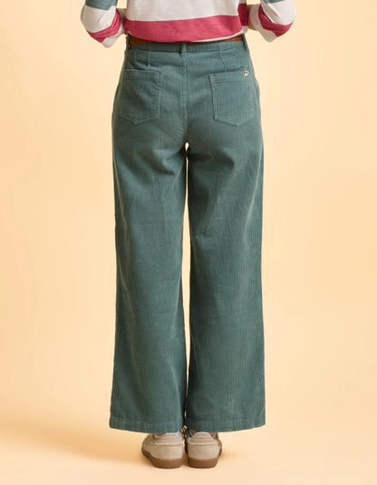 Person wearing teal wide-leg jeans on a beige background