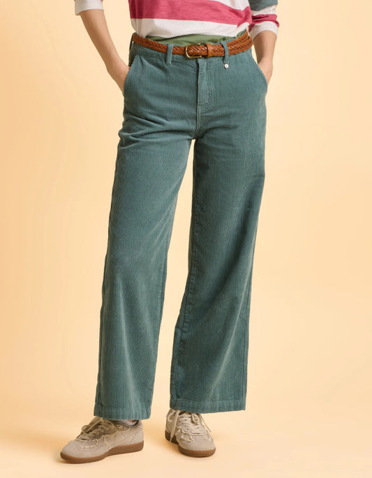 Person wearing teal pants and a striped shirt on a beige background