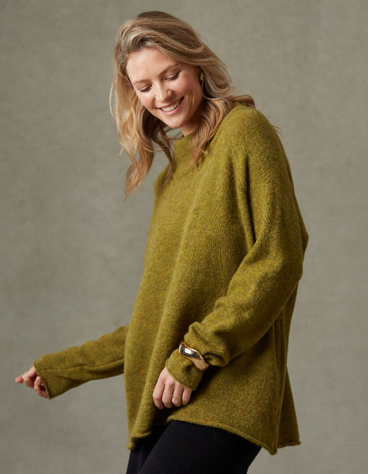 Woman wearing a green sweater against a plain background