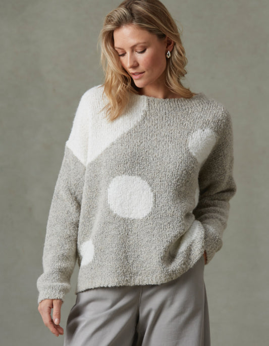 Woman wearing a gray sweater with white polka dots against a neutral background