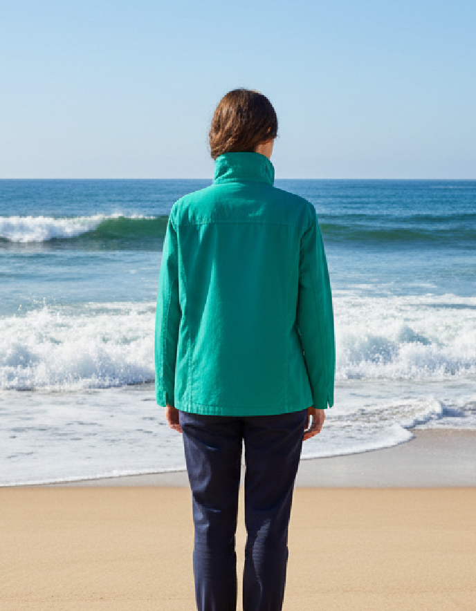 woman wearing jade green jacket on a beach