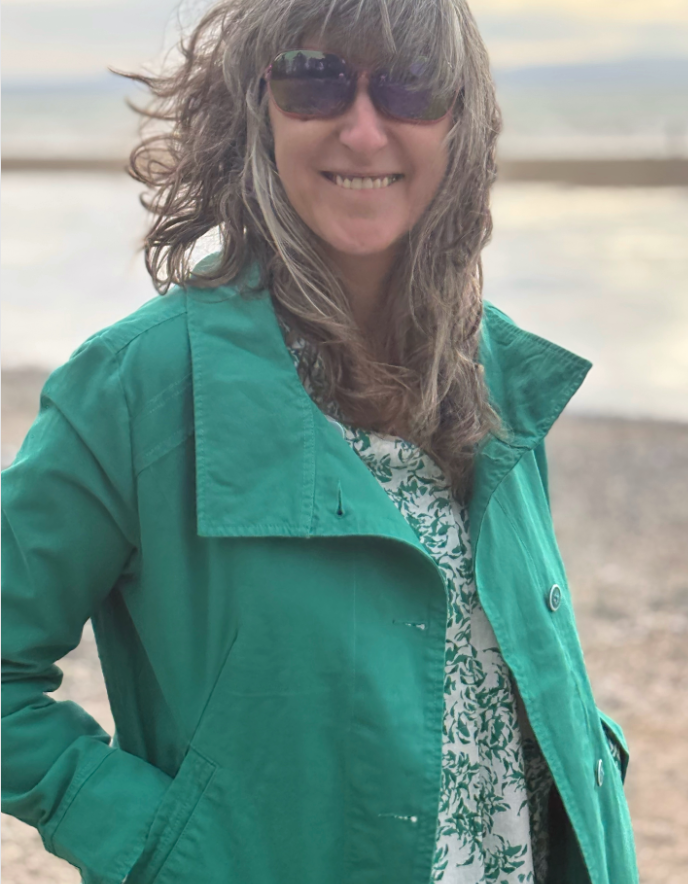 Person wearing a green jacket and sunglasses on a beach