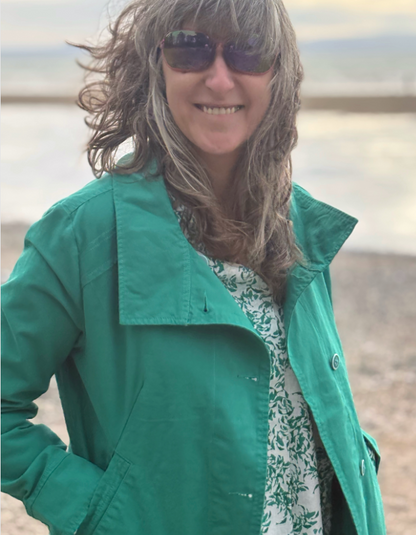 Person wearing a green jacket and sunglasses on a beach