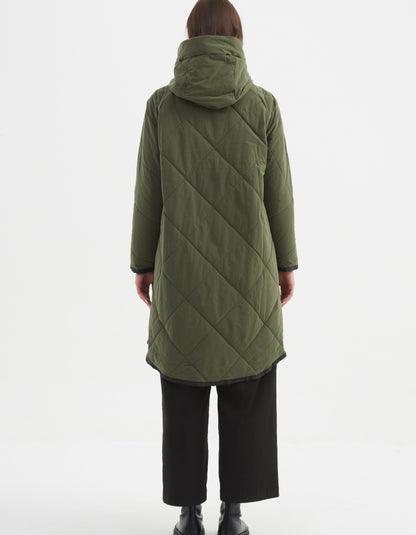 Person wearing a green quilted coat on a white background