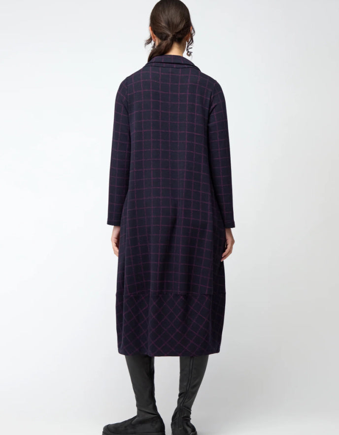 Woman wearing a long dark plaid bubble dress on a white background