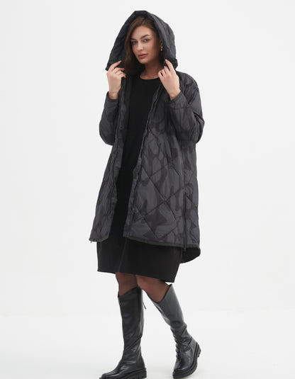 Woman wearing a dark grey and black blot print hooded coat on a white background