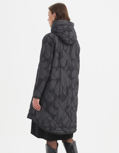 Woman wearing a long dark gray coat with a pattern on a white background